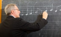 Man studying music notes on a blackboard
