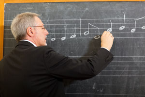 Man studying music notes on a blackboard