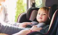Mother buckling child in car seat