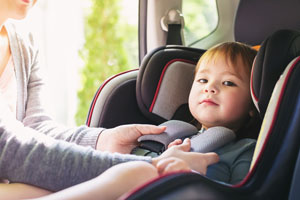 Mother buckling child in car seat