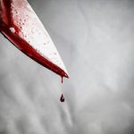 Closeup of a bloody knife with blood dripping