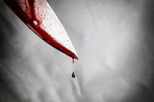 Closeup of a bloody knife with blood dripping